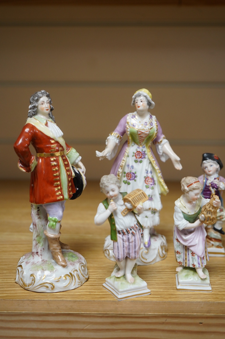 Eight various German porcelain figures, some with crossed sword marks to the bases and a floral encrusted pot and cover, largest 19cm high. Condition - fair, some losses